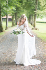 Full length portrait of beautiful sensual young blond bride in long white wedding dress and veil,...