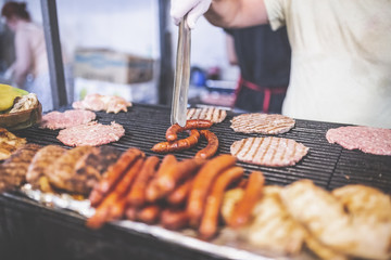 Street food barbecue burgers and sausages preparation. Fast food concept.