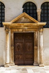 Fototapeta premium Old wooden door with stone ornaments and pilars on an old building.