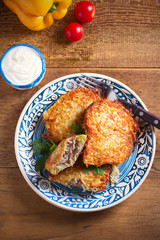 Potato Pancakes Filled With Meat. Vegetable fritters stuffed with meat on blue plate and sour cream or yogurt