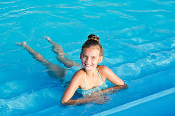 Cute smiling little girl child having fun in the swimming pool