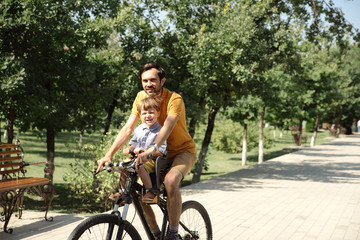 Bicycle ride of father and his son on baby seat