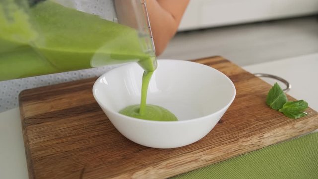 Woman cooking green avocado soup. Healthy cooking concept.