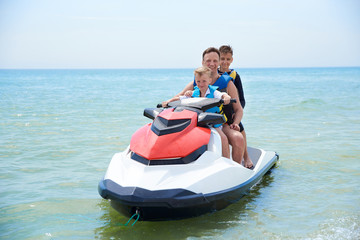 Fototapeta na wymiar FAMILY FATHER WITH SONS ON A HYDROCYCLE IN THE SEA