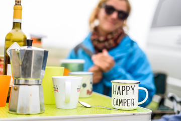 Woman camping travelling with breakfast mug and happy camper text.