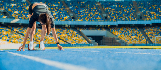 Female athlete taking position on her marks to start off the run