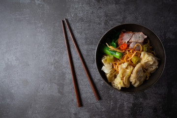 Egg noodle with red roasted pork and wonton on table.