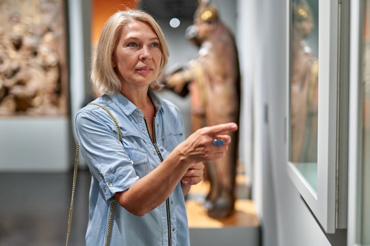 Mature woman visitor in the historical museum looking at pictures