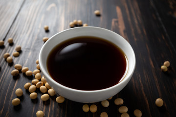 Soy sauce and soy bean on wooden table.