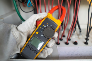 Workers use clamp meter to measure the current of electrical wires produced from solar energy for...