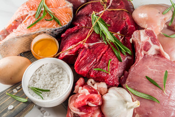 Carnivore diet background. Non vegan protein sources, Different meat food - chicken breast, pork steak, beef tenderloin, eggs, spices for cooking. White marble background copy space