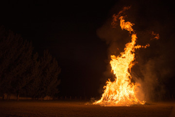 The flames of a larger campfire in the dark at night