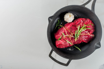 Raw beef tenderloin meat steak, with spices on a black cast iron skillet. Cooking food background.