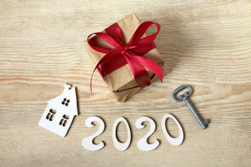 holiday gift, key, home and number 2020 on wooden table, top view. Congratulations on the new house
