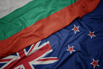 waving colorful flag of new zealand and national flag of bulgaria.