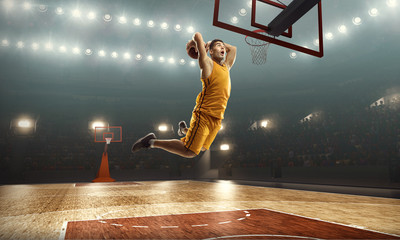 Basketball player scoring a slam dunk basket. Floodlit basketball court
