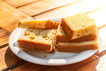 pieces of cake on a plate on a wooden table in the sun