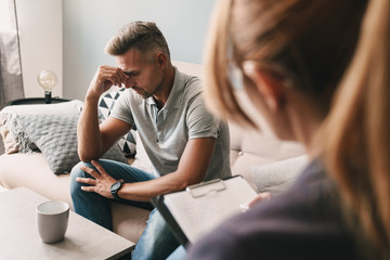 Photo of upset frustrated man having conversation with psychologist in room