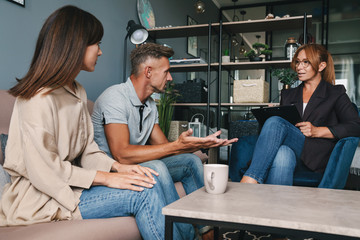 Fototapeta premium Zdjęcie miłej, skupionej pary rozmawiającej z psychologiem na sesji terapeutycznej w pokoju