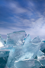 Fototapeta na wymiar Luminous transparent broken ice blocks on sky background, beautiful winter glacier landscape, vertical closeup view