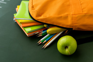 Back to school. Full school backpack isolated on blackboard