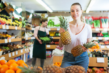 Obraz premium Young female holding fresh pineapples in fruit store