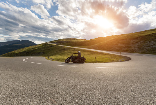 Motorcycle driver riding in Alpine landscape.