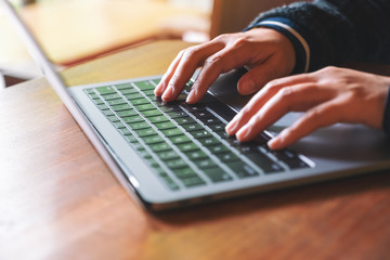 Closeup image of hands using and typing on laptop computer keyboard on the table