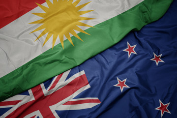 waving colorful flag of new zealand and national flag of kurdistan.