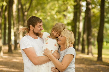 Three generation - grandmother, father, and little daughter. Family and people concept - happy excited smiling family at park outdoors