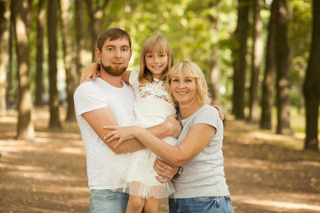 Fototapeta premium Three generation - grandmother, father, and little daughter. Family and people concept - happy excited smiling family at park outdoors