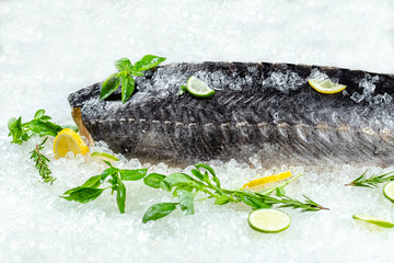fresh sea ocean sturgeon fish, lies on ice, without and with a head, cherry, slices of lemon and...