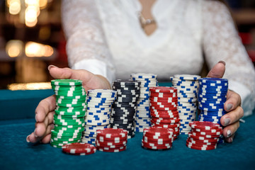 Female hands holding piles of casino chips on table