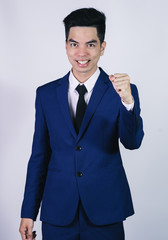 Portrait handsome young asian .businessman wearing a blue suit excitement or celebrating his victory sign isolated on grey background in studio. Asian man people. business success concept.