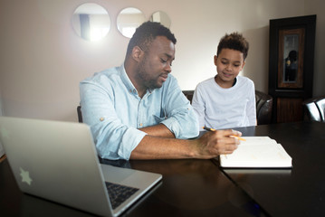 Fototapeta na wymiar Mixed family at home. African father and african american child. dad helping son with school homework. Education and relationship, man teaching and boy learning. home schooling.