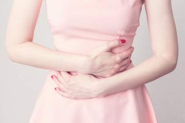 The woman has a stomach aches, ulcer or gastritis, woman's  hands, close up, cropped image, toned