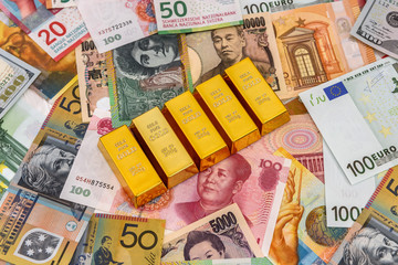 Gold bullion on colorful banknotes close up