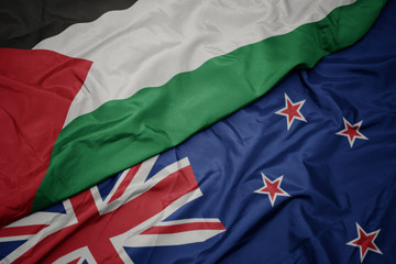 waving colorful flag of new zealand and national flag of palestine.