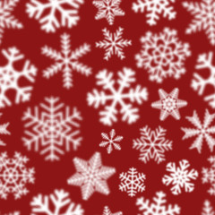 Christmas seamless pattern of white defocused snowflakes on red background
