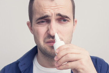 The man caught cold, sniffing nasal spray, medication for blocked nose, portrait, closeup