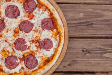 Italian Pepperoni pizza with salami on dark wooden background top view. Italian traditional food. Popular street food