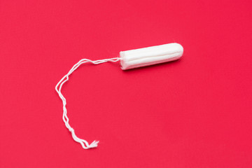 Tampon on a red background, close up, copy space, top view, menstrual period concept