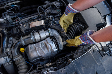 Mechanic examining car engine under hood close up