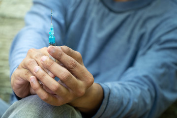 close up of Syringe and Needle in hand of drug addict man. homeless using needle injecting liquid....