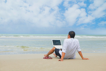 businessman working with computer on the beach. business man with laptop on colorful beach of island.