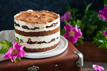 Birthday mousse cake with cocoa and rose hips flowers on an old vintage suitcase. selective focus. Bakery, confectionery, happy birthday concept