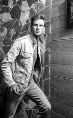 Young handsome man model against natural stone background. Black-white portrait.