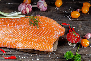 a large piece of red fish fillet with vegetables and spices and fresh herbs, stand and lie, from...