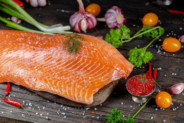 a large piece of red fish fillet with vegetables and spices and fresh herbs, stand and lie, from...