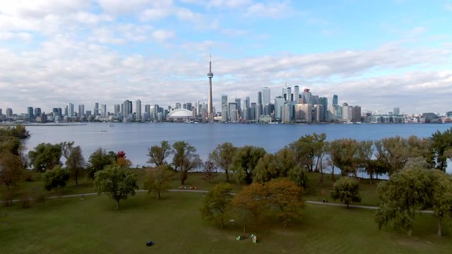 Toronto, Ontario, Canada, flyover shot of Centre Island and Lake Ontario showing downtown Toronto buildings by day during fall season.